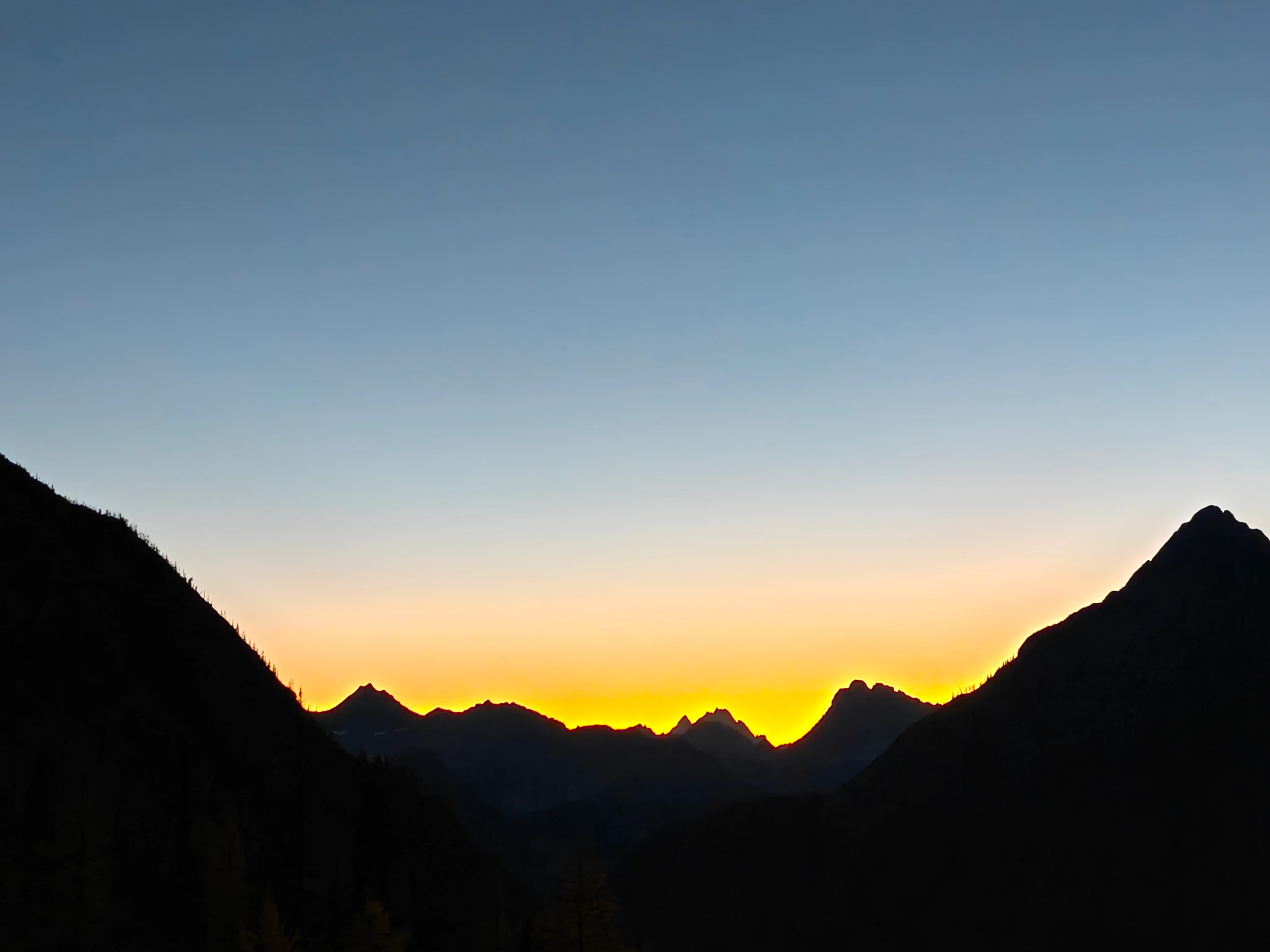 Mountain ridgelines silhouetted against a yellow sunset glow